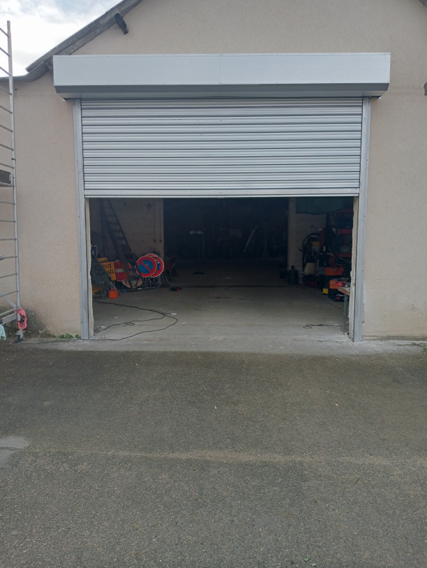 Emergency repair of a metal roller shutter at night with portable work lights, urban street in France, realistic photography, orange and black uniforms