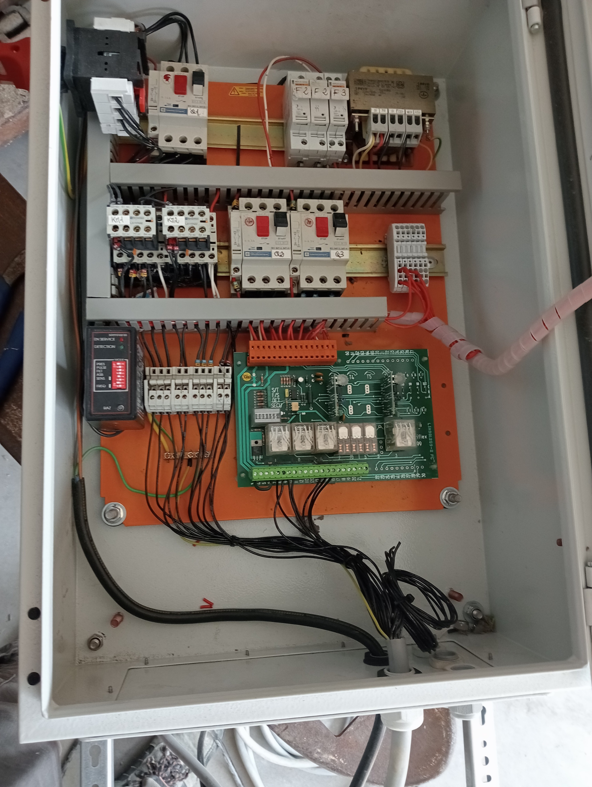 Professional electrician working inside an industrial electrical cabinet, tidy wiring, measuring instruments, PPE, orange and black brand accents, realistic photo